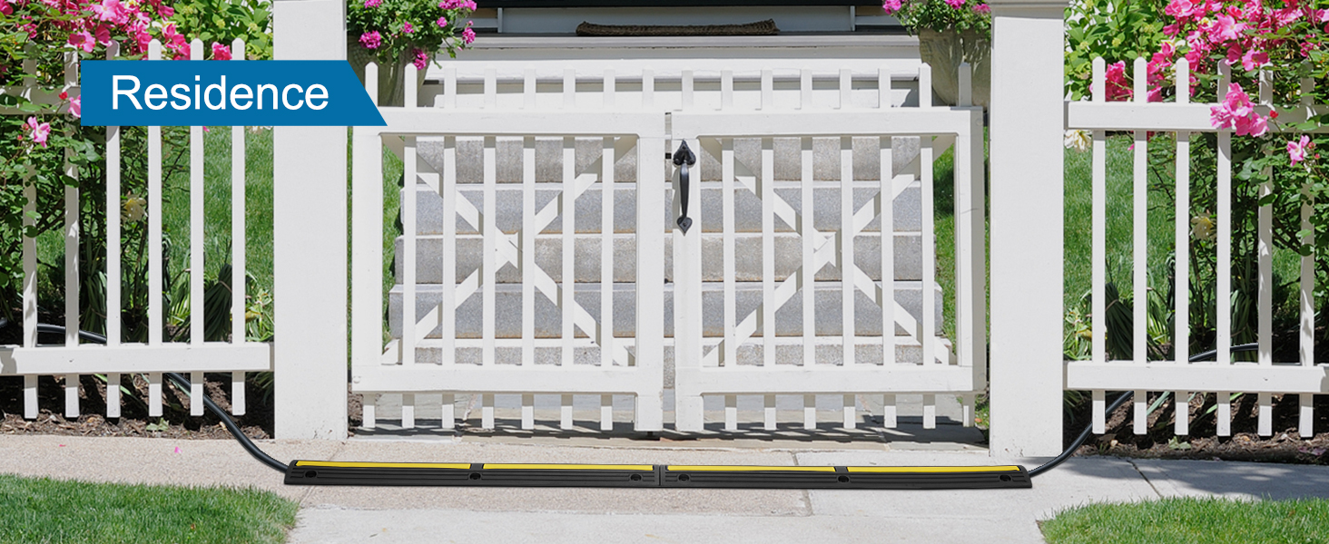 white picket fence with a VEVOR cable protector ramp and vibrant pink flowers.