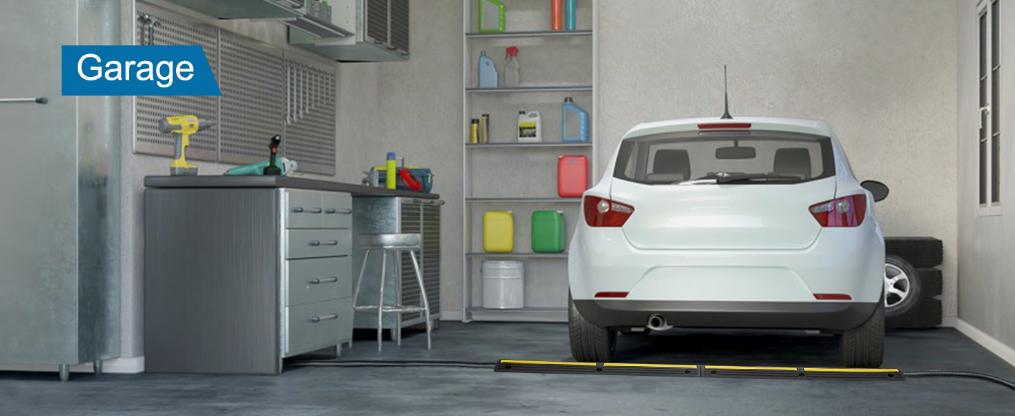 white car in a garage with VEVOR cable protector ramp near rear tires, workbench and storage shelves in view.