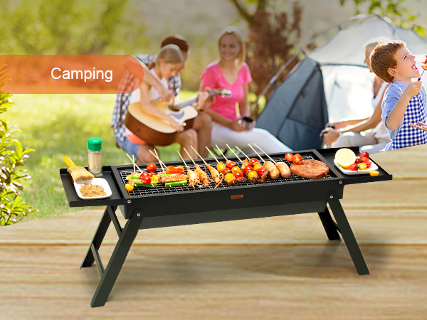 VEVOR portable charcoal grill at a camping site with skewers, spices, and a tent in the background.