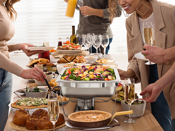 people enjoying a buffet with VEVOR chafing dish set, various foods, and drinks on a long table.