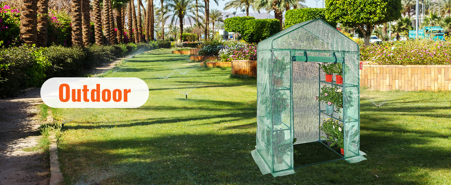 VEVOR walk-in greenhouse outside on a neatly manicured lawn with plants and palm trees in the background.