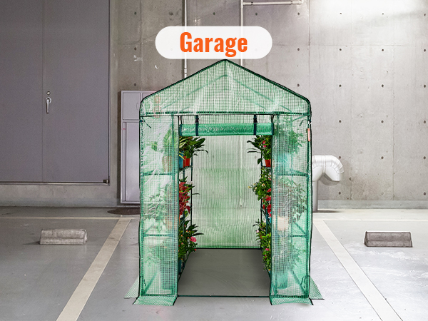 VEVOR walk-in greenhouse in a concrete garage, filled with potted plants along the sides.